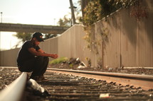 Man sitting on railroad tracks