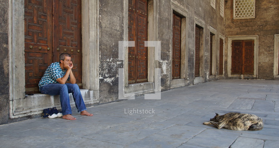A Muslim man and his dog sleeping inside the courtyard of the Blue Mosque, Istanbul.