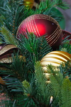 Red and gold ball Chrostmas ornaments on pine needles.