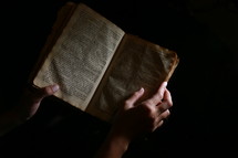 hands on the pages of a Bible