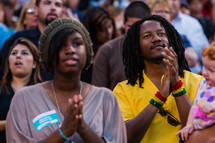 Black man and woman in church service clapping hands in praise and worship service 