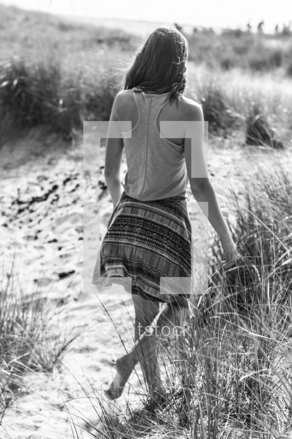 woman walking barefoot in the sand 