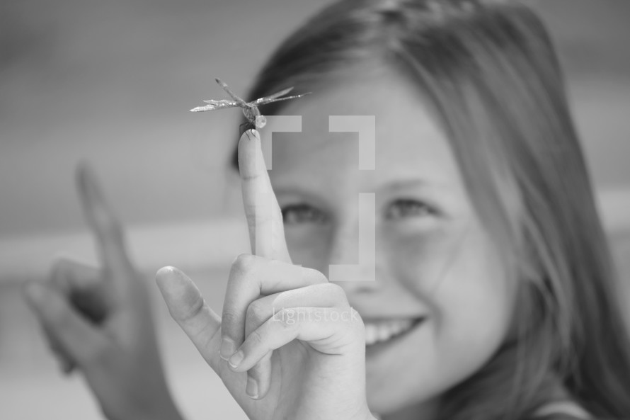 a little girl catching a dragonfly on her finger 