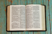 pages of a Bible opened to Psalms on a weathered teal wood table 