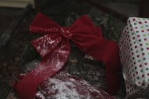Red bow and wrapped Christmas presents with snow.