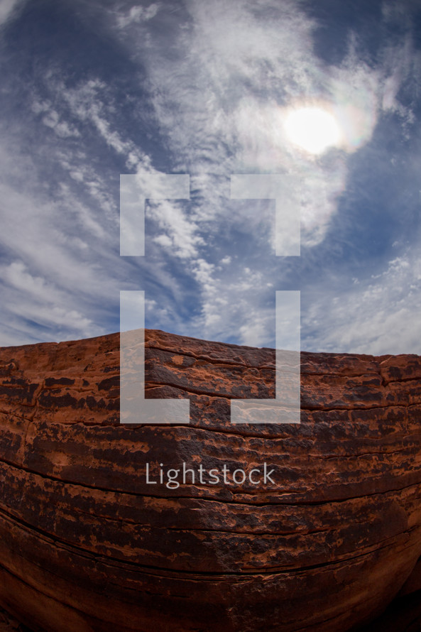red rock cliff and clouds in a blue sky 
