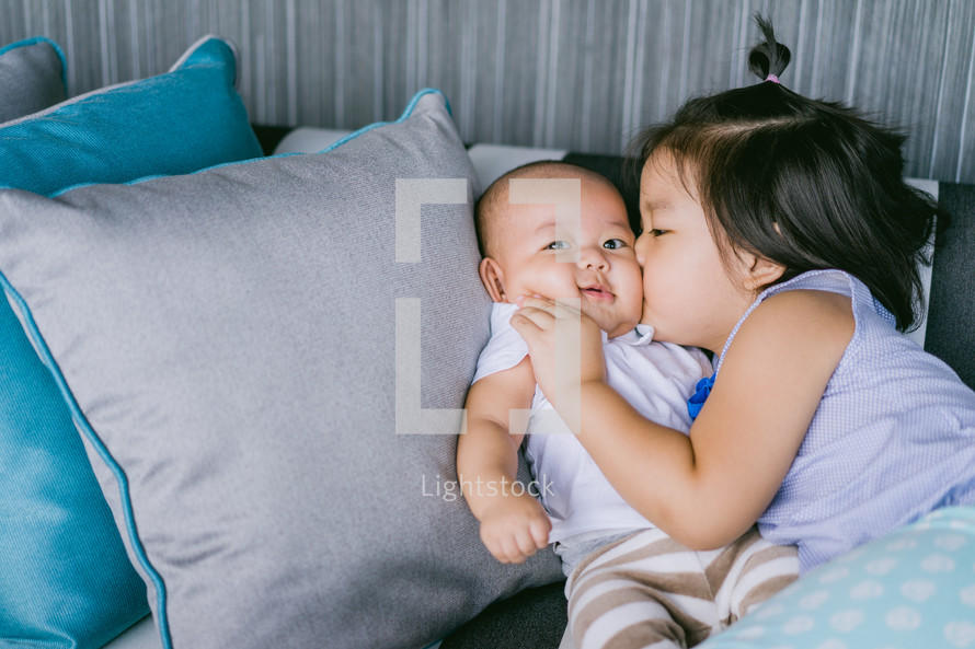 a big sister kissing her baby brother 