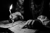 Ukrainian woman reading ancient book - Bible. Concentrated follows finger on paper page under candle light. History of Kyiv Rus. Psalter, 19th century, prayers and psalms.