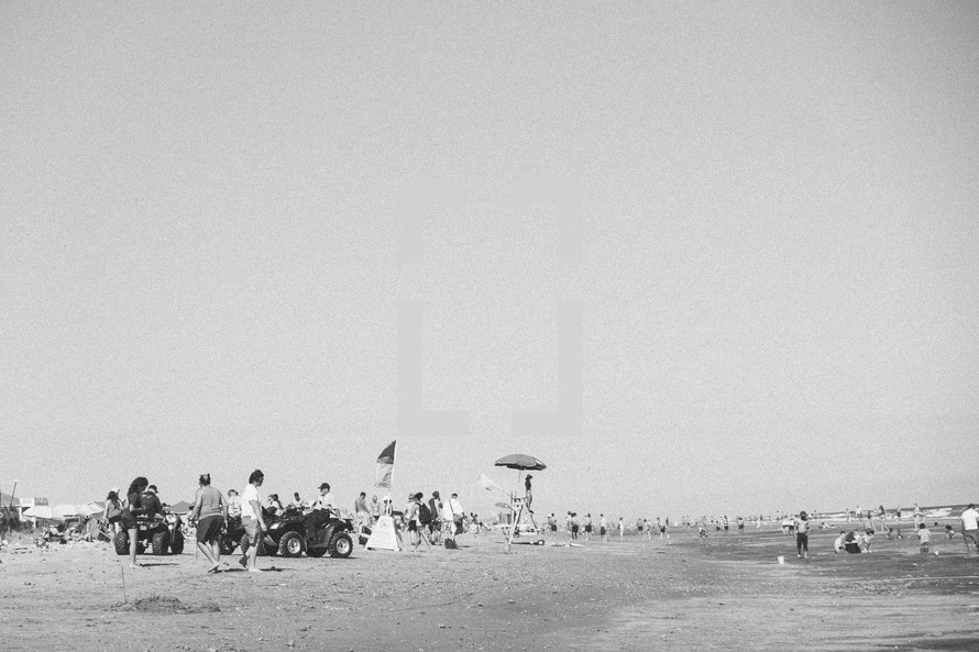 crowds of people and lifeguard on a 4-wheeler on a beach 