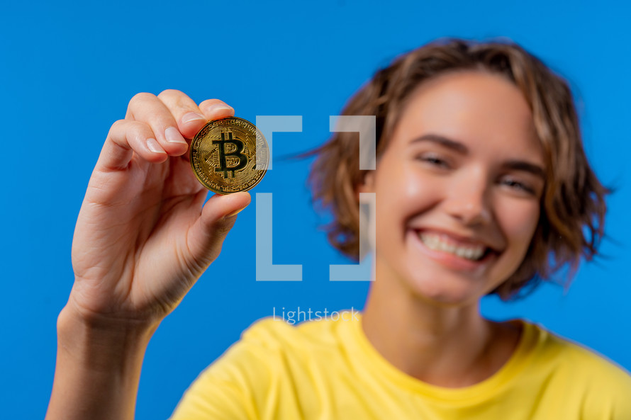 Woman with bitcoin, crypto currency. Golden coin on blue background. Digital exchange, popularity of BTC, symbol of future money, electronics industry, mining concept. High quality photo