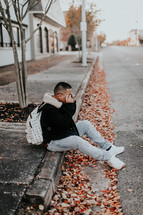 a man sitting on a curb in fall 