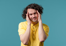 Young man having headache, blood pressure, blue studio portrait. Guy putting hands on head, isolated on violet background. Concept of problems, medicine, illness. High quality