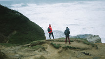 men with backpacks standing at the edge of a cliff 