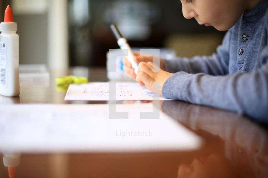 child doing school work with a marker 