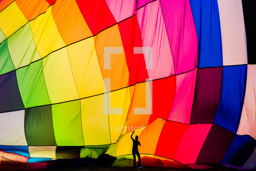 Man in front of a rainbow colored hot air balloon perspective, scale