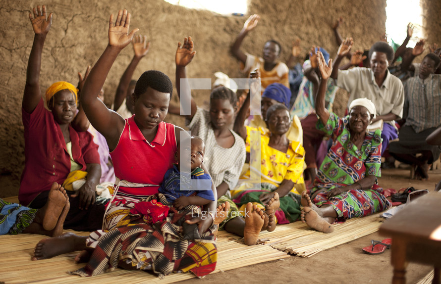 A group of Ugandan women lift their hands in prayer