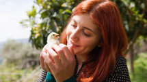 Young woman red hair holds a chick in her hands
