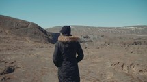 a woman walking over a barren landscape 