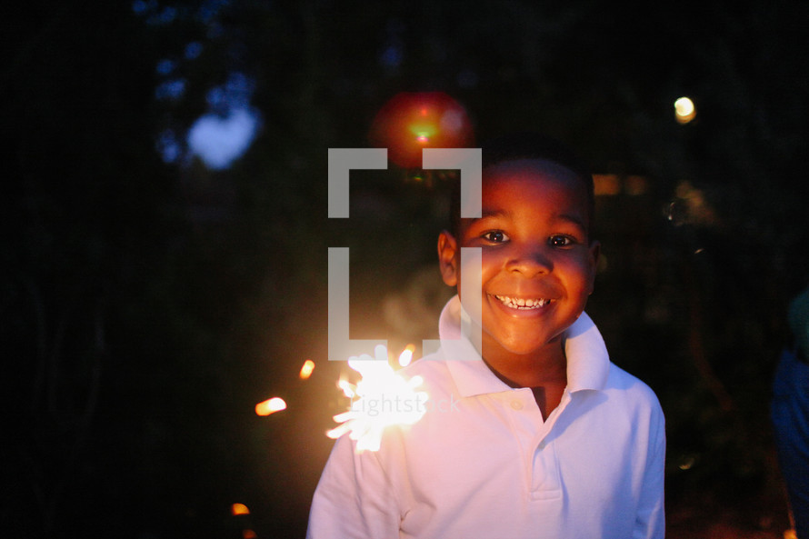 boy with a smile holding a sparkler