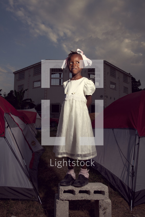 girl in dress standing next to tents