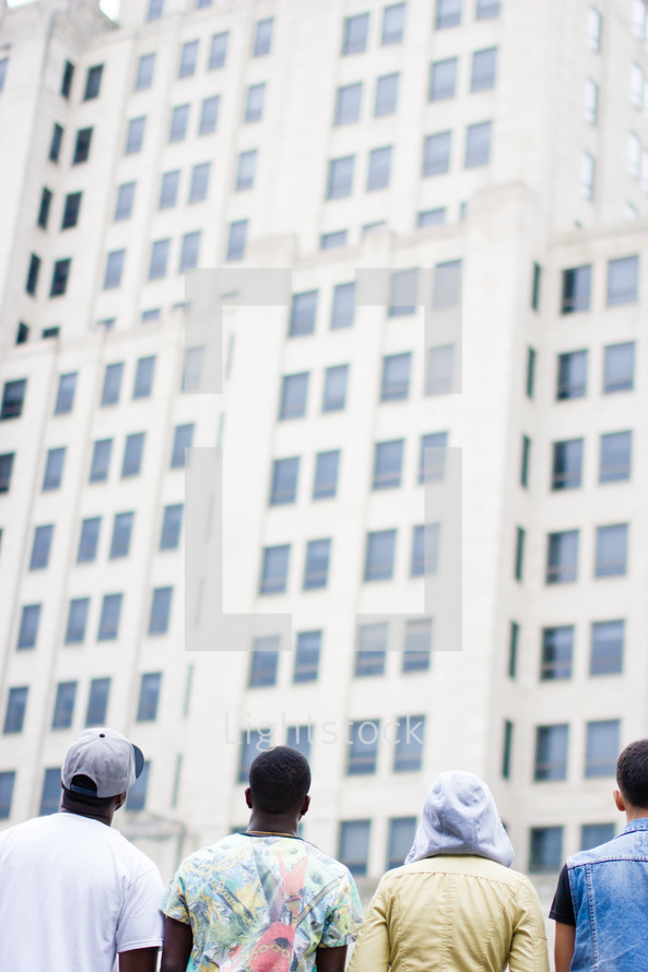 Backs of African-american teens looking at a building.