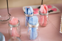 Jars of plastic ware on a table with candy.