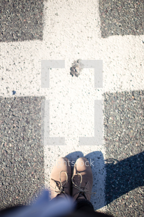 Feet on the pavement in an intersection.