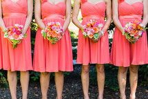  Bridesmaids holding bouquets of flowers dresses girls florals orange pink 