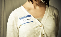 woman wearing a name tag with the words VISITOR