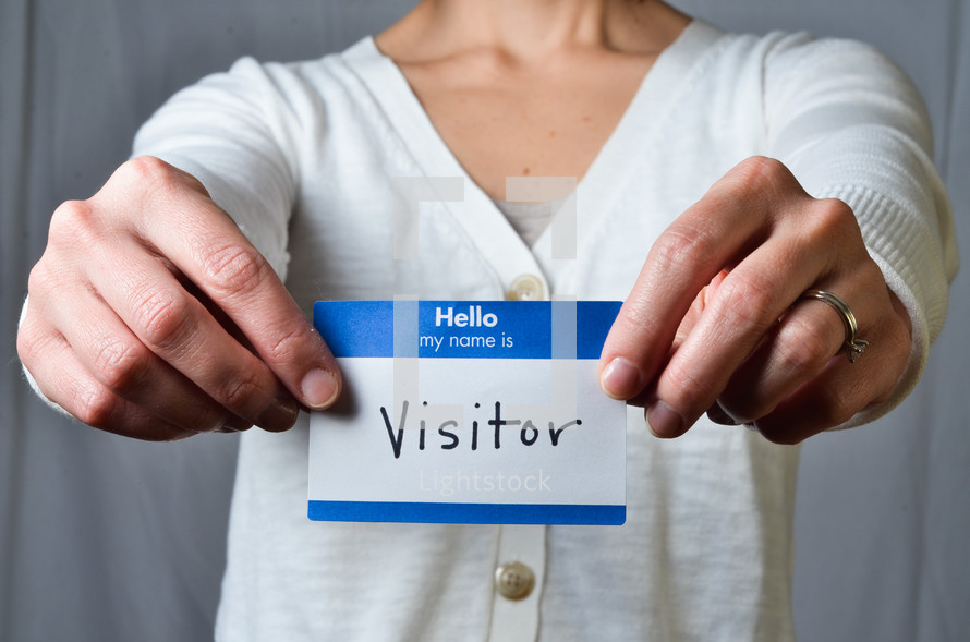 woman holding a name tag with the words visitor 