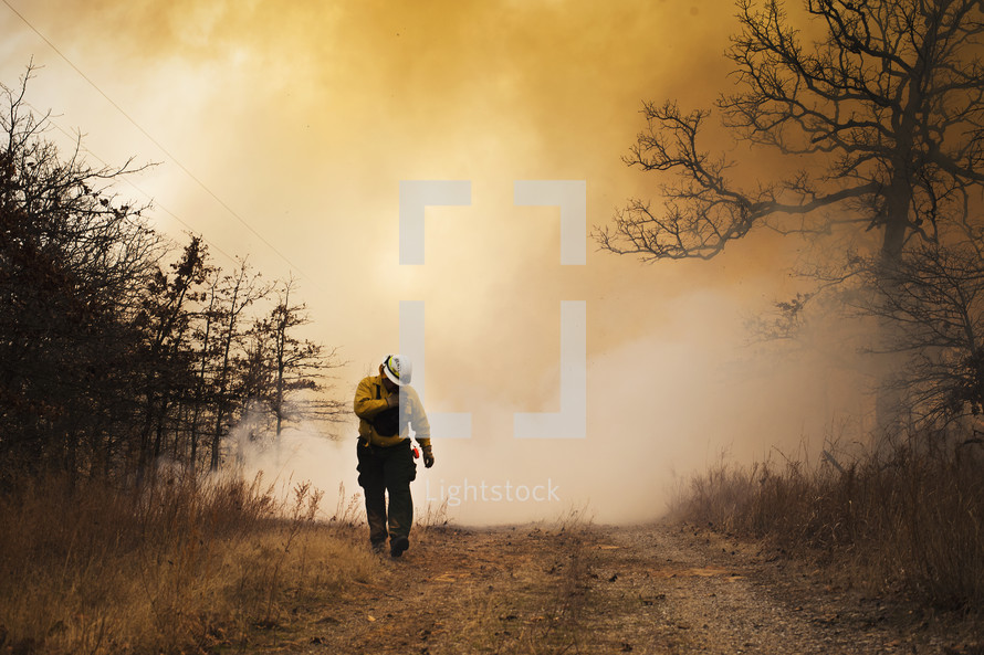 firefighter walking in front of smoke from a forest fire