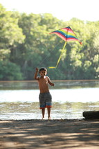 Boy flying kite by the river