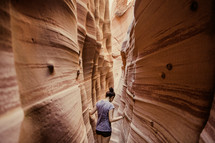woman exploring narrow red rock canyon 