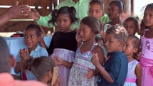 Children clapping and singing in a small church service in Honduras