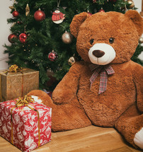 Teddy bear near christmas tree with gifts