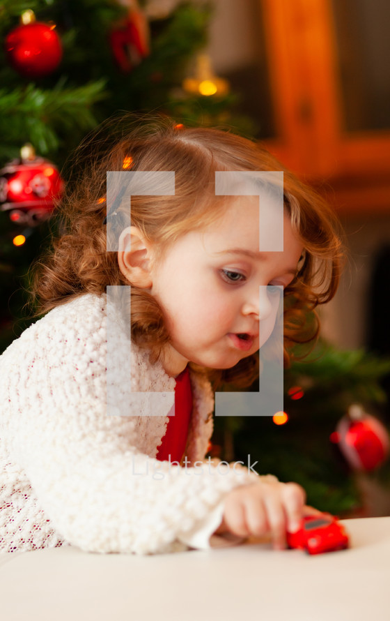 girl playing with a toy car at Christmas 