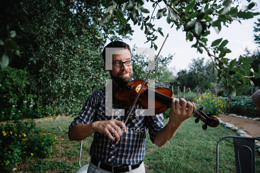 man playing a fiddle outdoors 