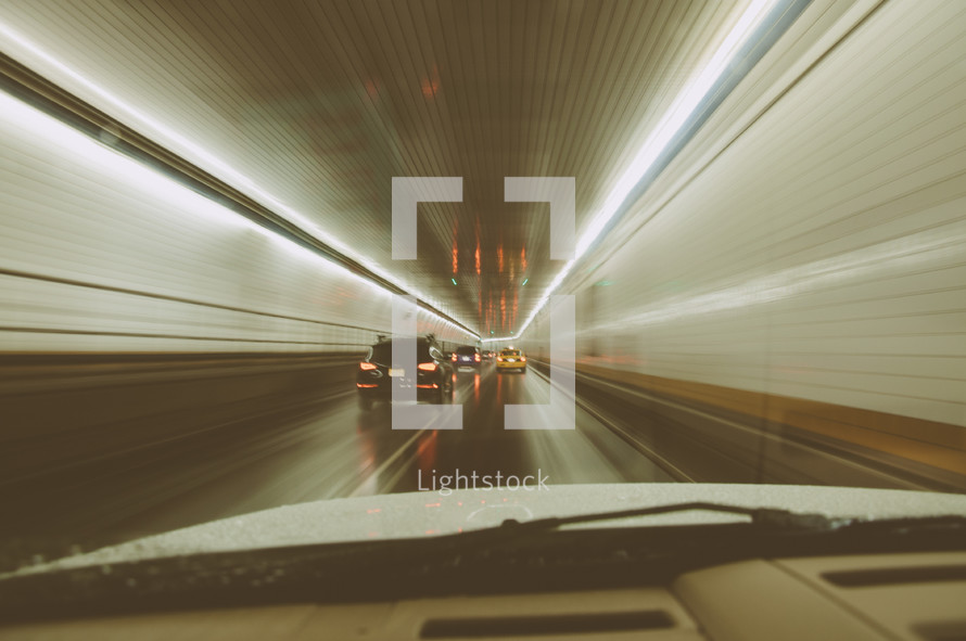 Photo of car driving through New York tunnel showing motion blur.