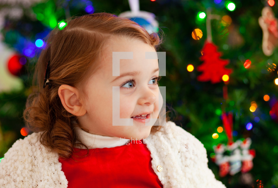 Portrait of a little child with red dress near Christmas tree