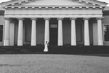 a bride and groom on steps in front of a grand building 