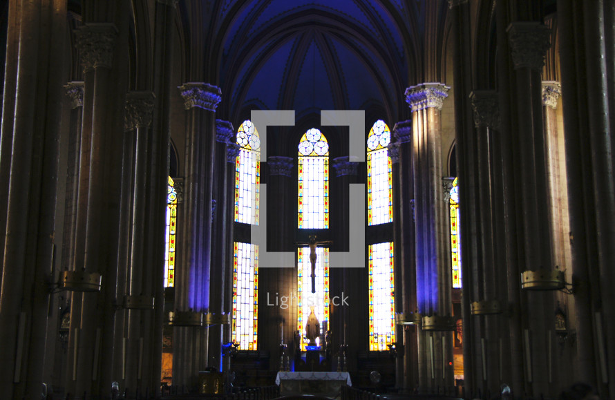 Interior of cathedral with light shining through stained glass windows.