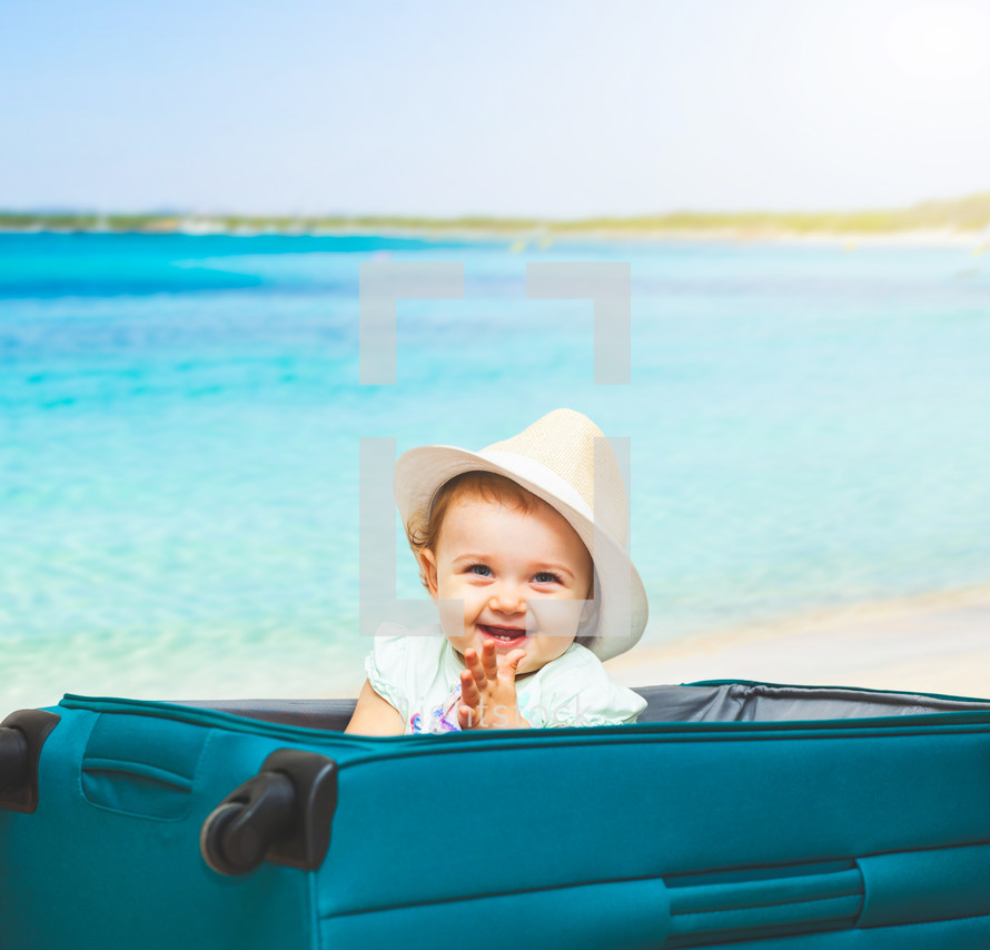 baby girl in a suitcase with a beach scene 