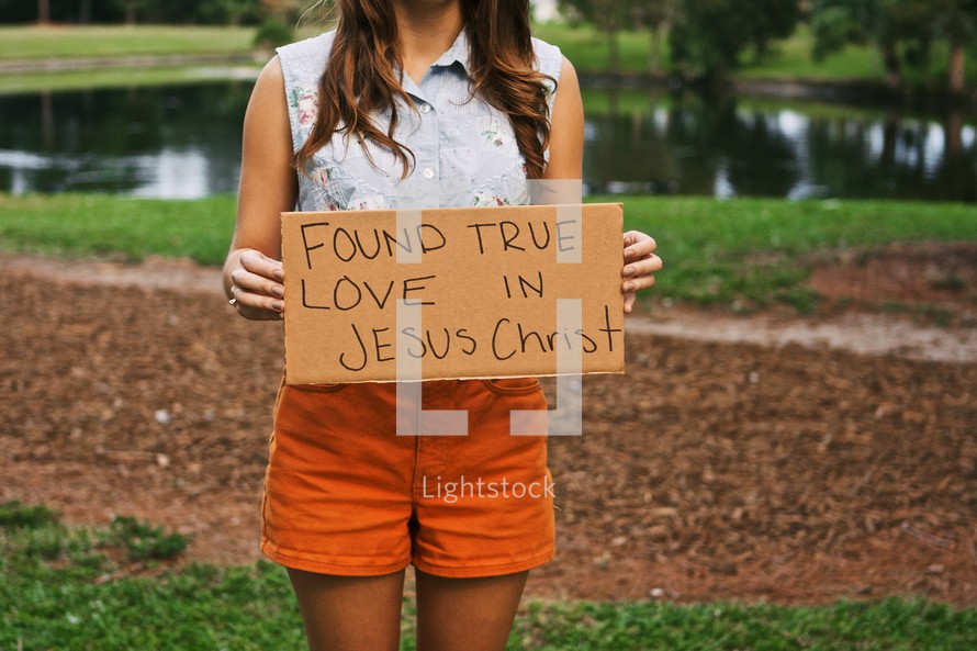 Woman holding a sign with the words FOUND LOVE IN JESUS CHRIST