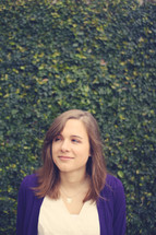 headshot of a young woman standing in front of an ivy wall 