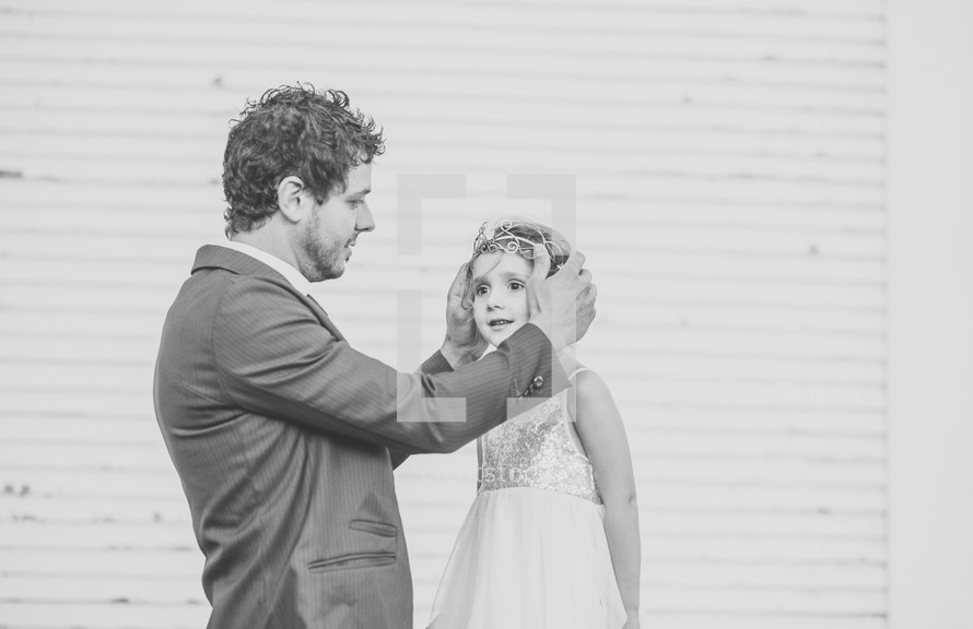 a father putting a tiara on his daughter 