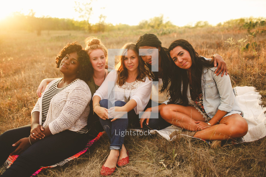 portrait of friends sitting on blankets in the grass 