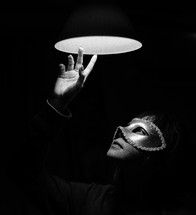a woman in a mask looking up at a light 