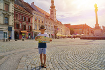 Young boy tourist with city map stay on the old european street