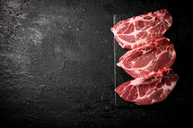 Raw pork steak on a stone board. On a black background. High quality photo