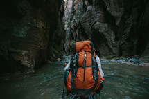 hiking through a river at the bottom of a canyon 